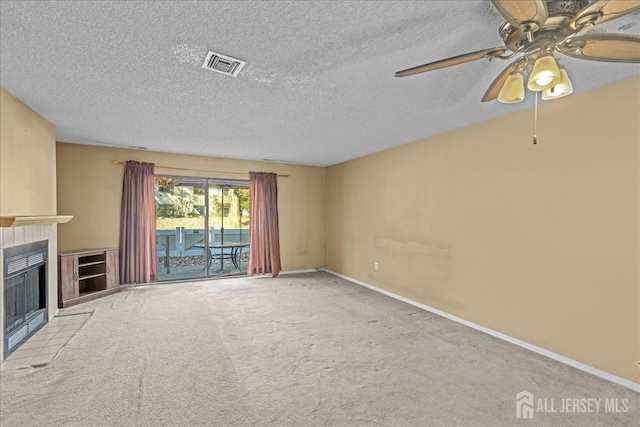 unfurnished living room with a tile fireplace, a textured ceiling, light carpet, and ceiling fan