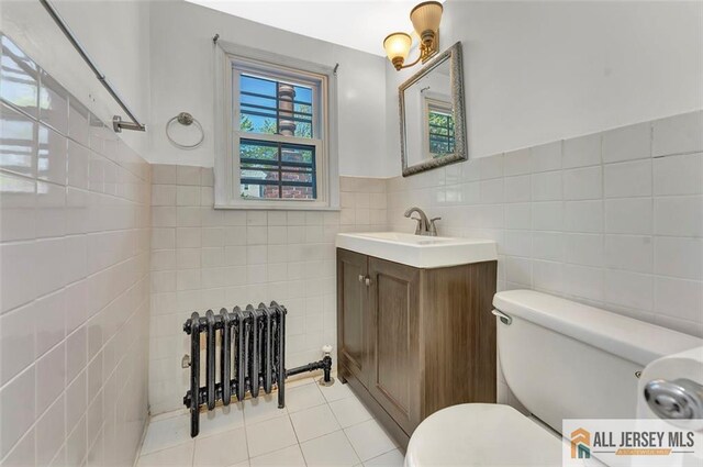 224 2nd St, South Amboy, NJ 08879 - bathroom with tile walls, tile patterned floors, vanity, toilet, and radiator heating unit