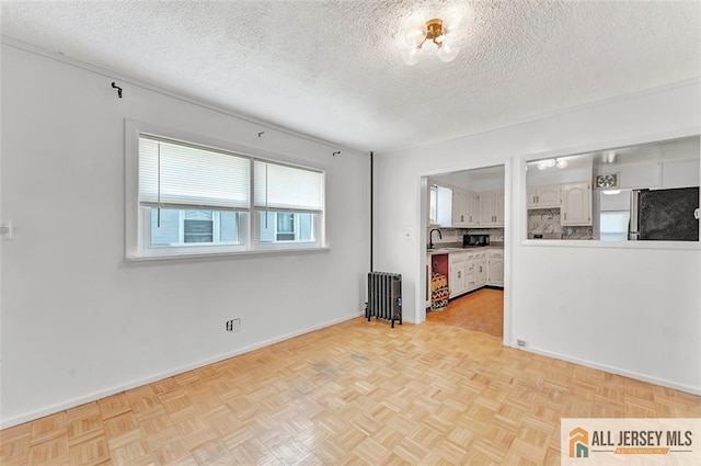 224 2nd St, South Amboy, NJ 08879 - unfurnished living room with baseboards, radiator heating unit, a sink, and a textured ceiling