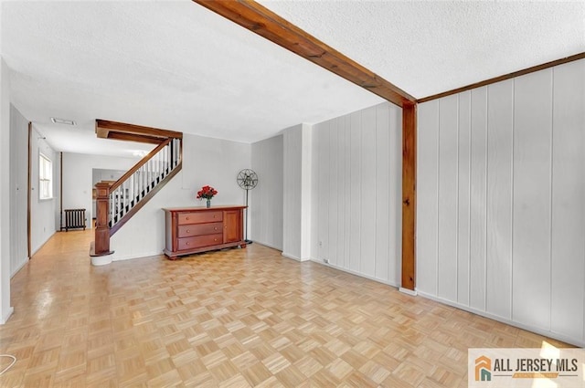 224 2nd St, South Amboy, NJ 08879 - unfurnished living room featuring a textured ceiling, stairway, baseboards, and radiator heating unit