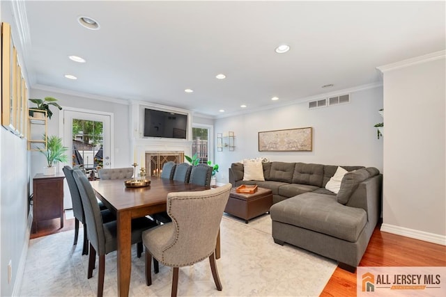 43 S Brook Dr, Milltown, NJ 08850 - dining space featuring light wood finished floors, crown molding, recessed lighting, and a warm lit fireplace