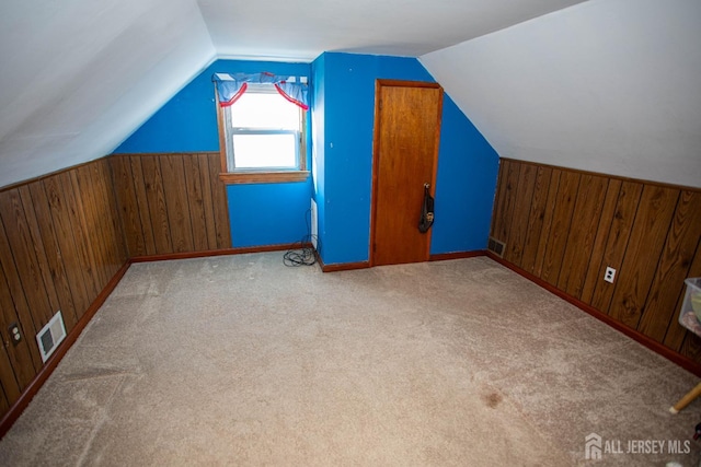 additional living space with lofted ceiling, carpet, and wood walls