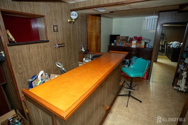 bar with light tile patterned floors and wood walls