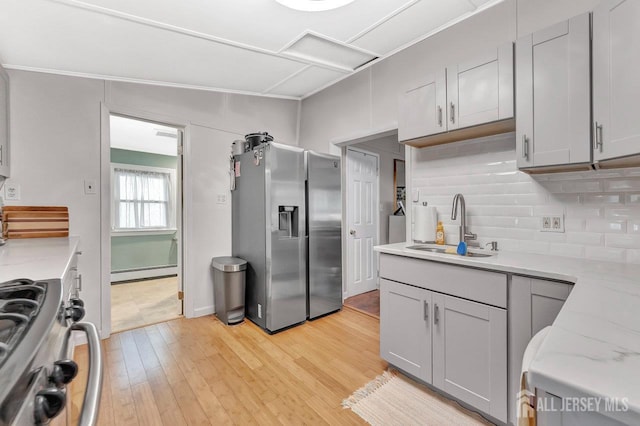 220 Birchwood Dr, Old Bridge, NJ 07735 - kitchen with stainless steel appliances, a sink, a baseboard heating unit, backsplash, and light wood-style flooring