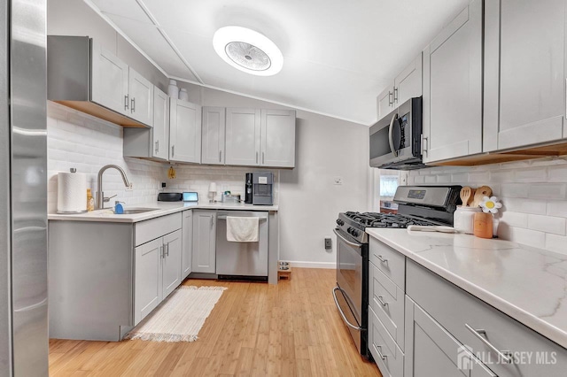 220 Birchwood Dr, Old Bridge, NJ 07735 - kitchen featuring appliances with stainless steel finishes, a sink, decorative backsplash, light wood-style flooring, and vaulted ceiling