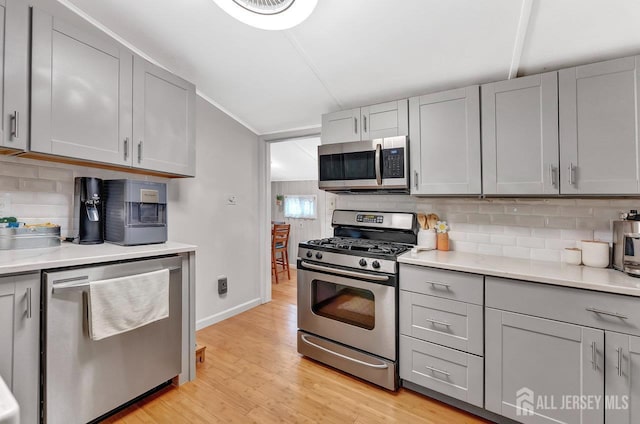 220 Birchwood Dr, Old Bridge, NJ 07735 - kitchen featuring appliances with stainless steel finishes, gray cabinets, light wood-type flooring, tasteful backsplash, and baseboards