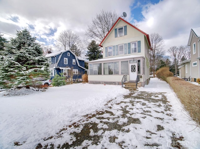 view of front of house with entry steps, a sunroom, and a gambrel roof