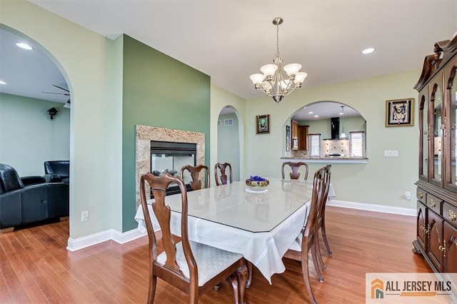 dining space featuring an inviting chandelier, a high end fireplace, and light hardwood / wood-style flooring