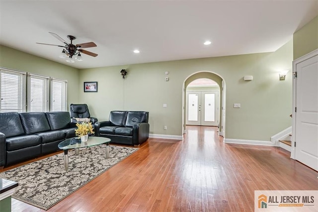 living room with french doors, ceiling fan, and light wood-type flooring