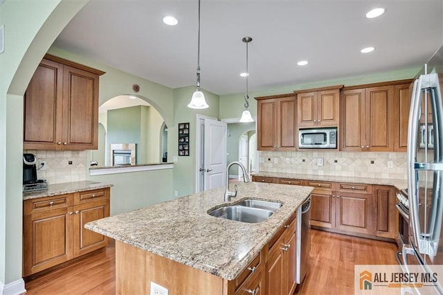 kitchen featuring sink, tasteful backsplash, a center island with sink, appliances with stainless steel finishes, and pendant lighting