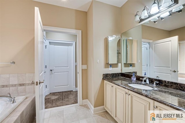 bathroom featuring tile patterned floors, vanity, and tiled bath