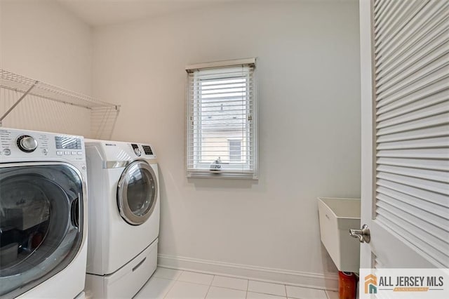 laundry room featuring washing machine and clothes dryer and light tile patterned flooring