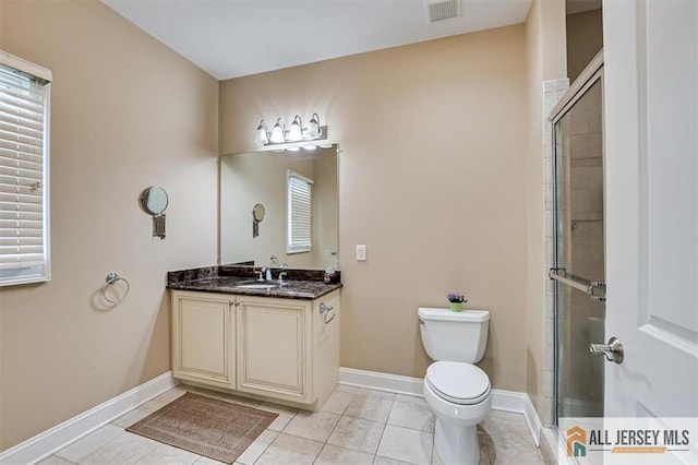 bathroom with tile patterned flooring, vanity, a shower with door, and toilet