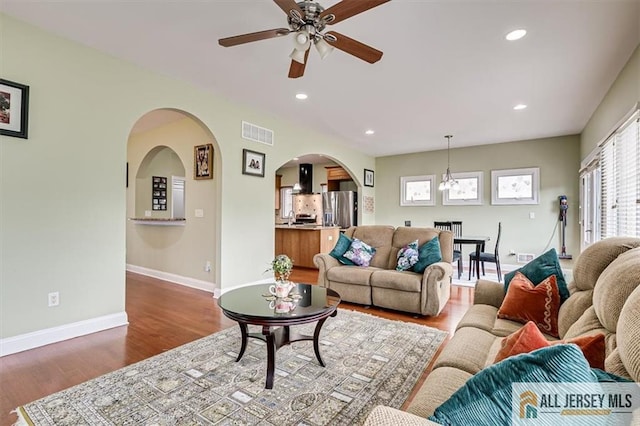 living room featuring sink, ceiling fan with notable chandelier, and wood-type flooring