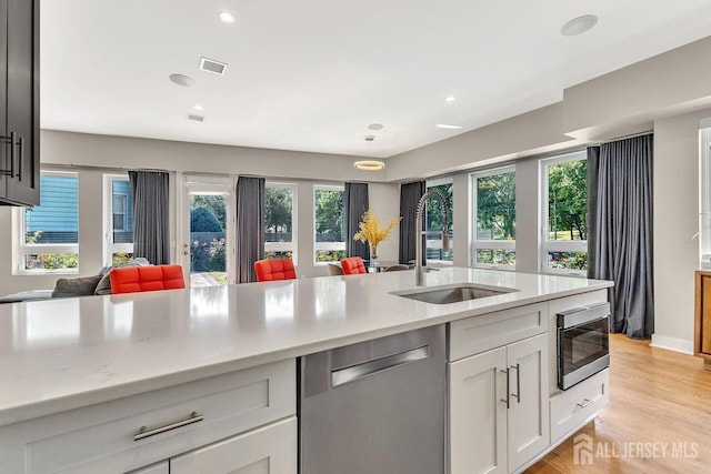 kitchen with appliances with stainless steel finishes, light wood-type flooring, white cabinetry, and plenty of natural light