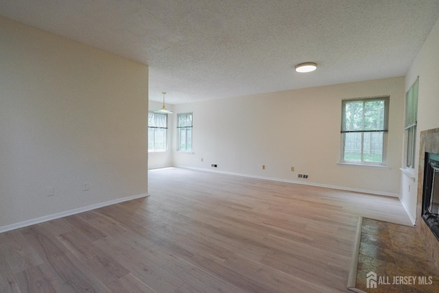 14 Carriage Pl, Edison, NJ 08820 - unfurnished living room featuring a tile fireplace, healthy amount of natural light, light wood-style flooring, and a textured ceiling