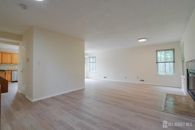 14 Carriage Pl, Edison, NJ 08820 - unfurnished living room featuring light wood-style flooring, a tiled fireplace, and a textured ceiling