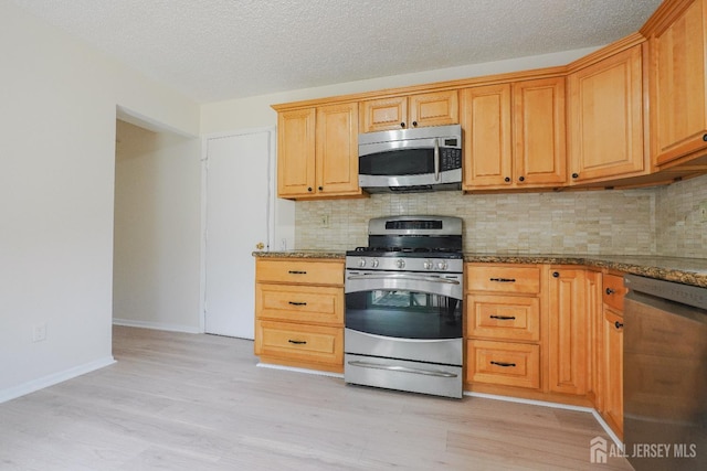14 Carriage Pl, Edison, NJ 08820 - kitchen featuring appliances with stainless steel finishes, tasteful backsplash, light wood-style flooring, dark stone countertops, and a textured ceiling