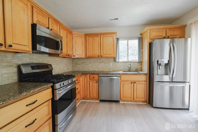14 Carriage Pl, Edison, NJ 08820 - kitchen with stainless steel appliances, light wood finished floors, a textured ceiling, dark stone counters, and backsplash