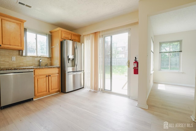 14 Carriage Pl, Edison, NJ 08820 - kitchen with appliances with stainless steel finishes, light wood-type flooring, plenty of natural light, decorative backsplash, and a textured ceiling