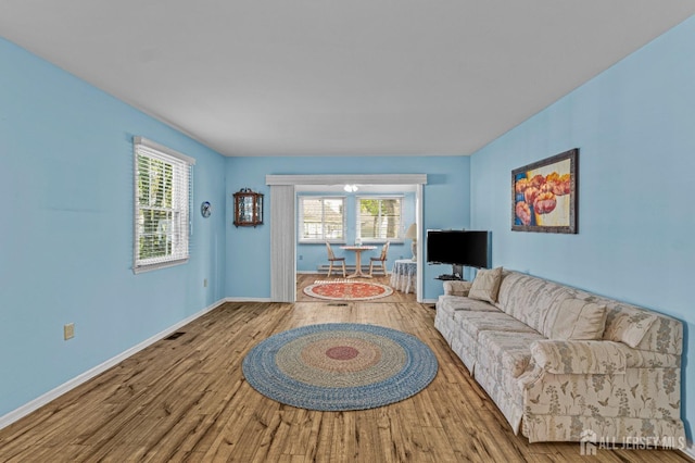 living room featuring visible vents, baseboards, and wood finished floors