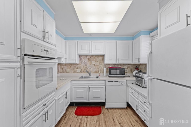 kitchen featuring white appliances, white cabinetry, and a sink