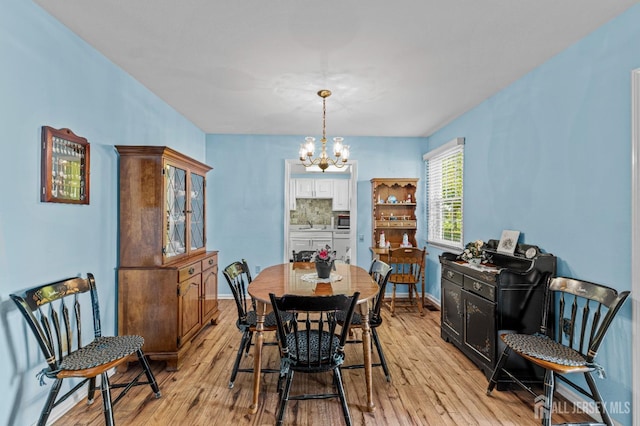 dining space featuring light wood-style floors, baseboards, and a notable chandelier