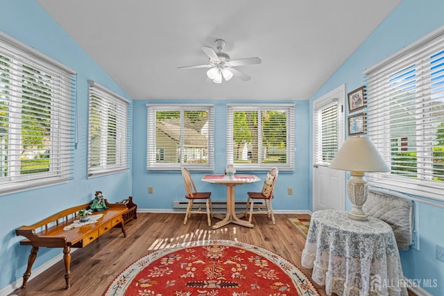 sunroom / solarium featuring a baseboard heating unit, vaulted ceiling, and a ceiling fan