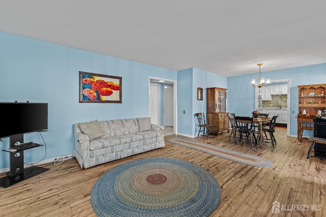 living area featuring a chandelier, light wood-type flooring, and baseboards