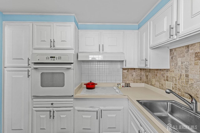 kitchen featuring white appliances, a sink, white cabinetry, and tasteful backsplash