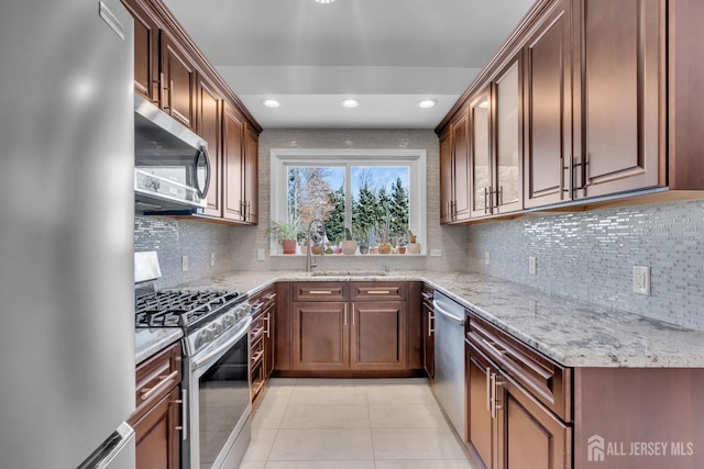 kitchen featuring light stone countertops, decorative backsplash, sink, stainless steel appliances, and light tile patterned flooring