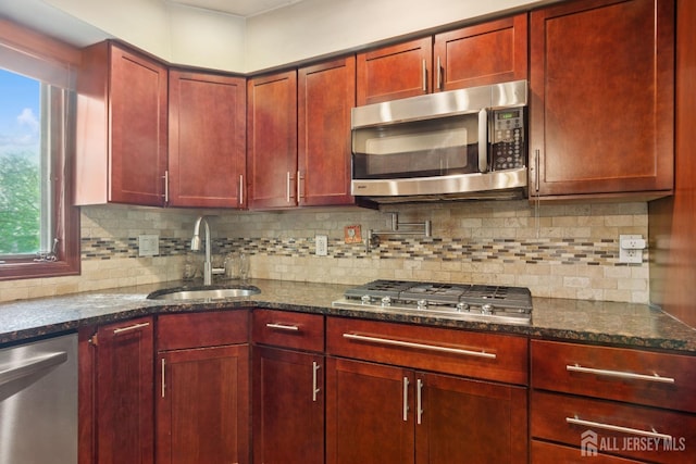 kitchen with a sink, stainless steel appliances, reddish brown cabinets, and plenty of natural light