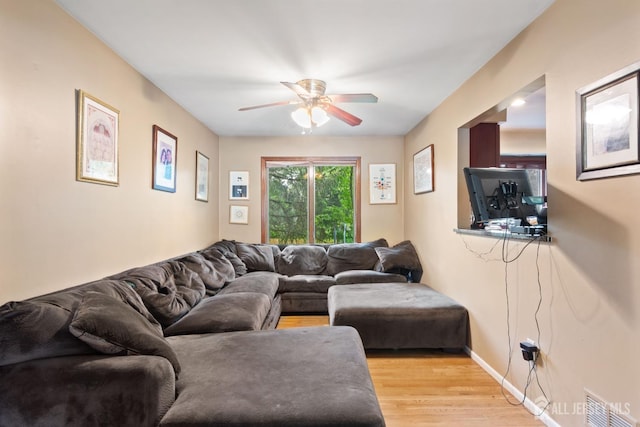 living room with baseboards, a ceiling fan, visible vents, and light wood-style floors