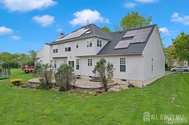 65 Cortland Dr, East Brunswick, NJ 08816 - back of house with roof mounted solar panels, a yard, a chimney, and roof with shingles