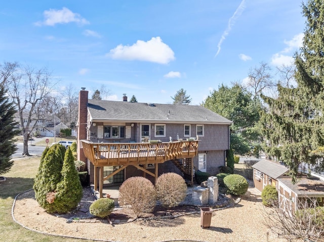 rear view of property featuring a chimney, stairway, a wooden deck, and a shingled roof