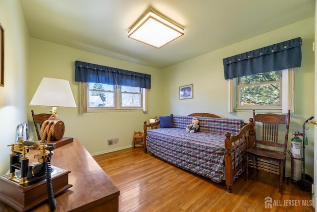 bedroom featuring visible vents, hardwood / wood-style floors, and baseboards