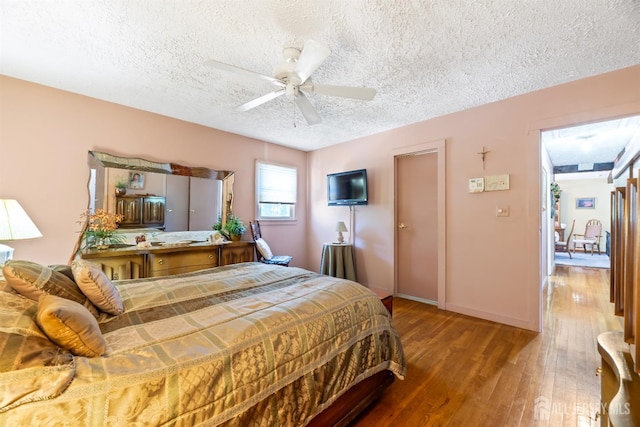bedroom with a textured ceiling, ceiling fan, and wood finished floors