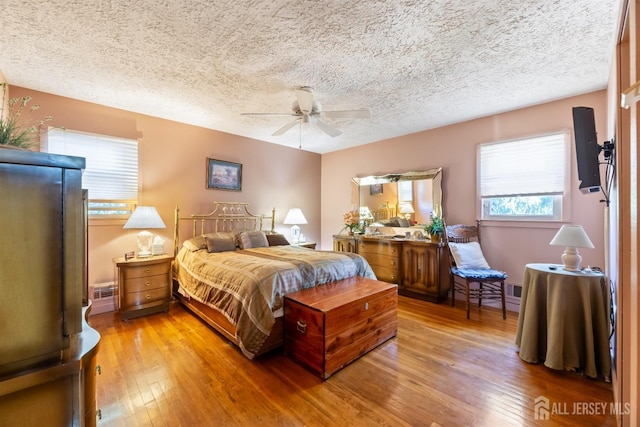 bedroom featuring a textured ceiling, hardwood / wood-style floors, and a ceiling fan