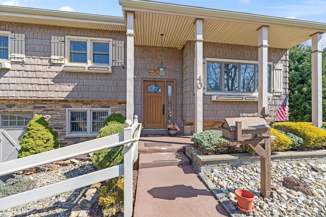 view of exterior entry with covered porch and stone siding
