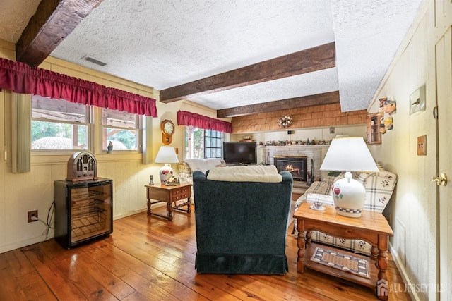 living area with wood-type flooring, a textured ceiling, and beam ceiling