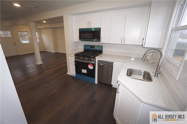 kitchen featuring visible vents, dark wood finished floors, a sink, stainless steel appliances, and white cabinets