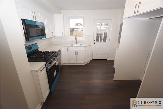 kitchen with dark wood finished floors, a sink, light countertops, appliances with stainless steel finishes, and white cabinetry