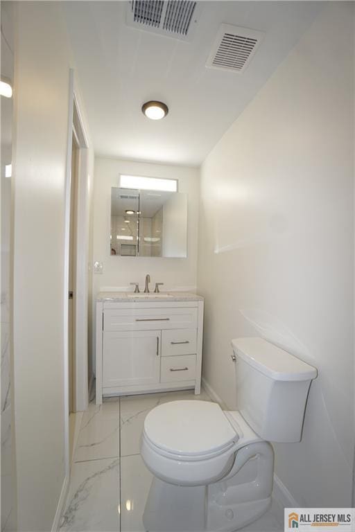 bathroom featuring vanity, toilet, visible vents, and marble finish floor