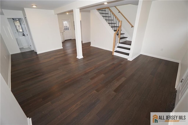 basement with stairs, dark wood-style floors, and baseboards