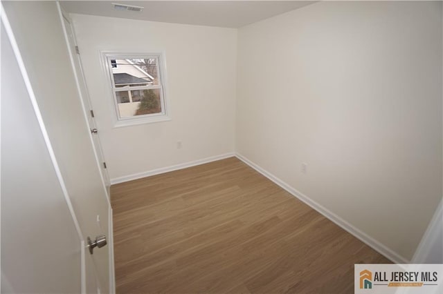 unfurnished room with visible vents, wood finished floors, and baseboards