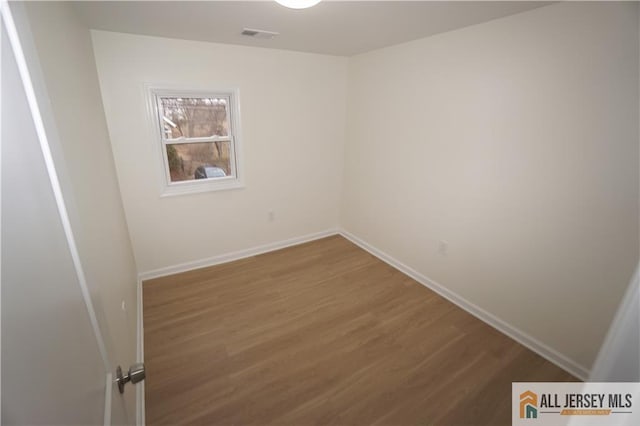 spare room featuring visible vents, wood finished floors, and baseboards