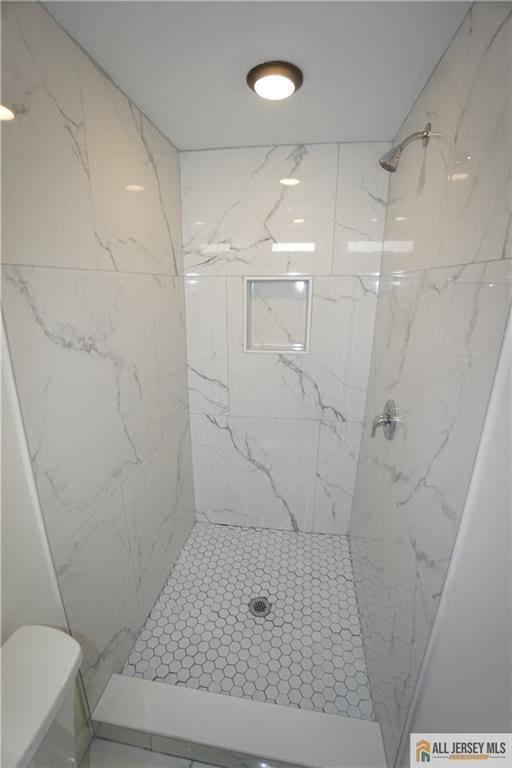 bathroom featuring toilet and a tile shower