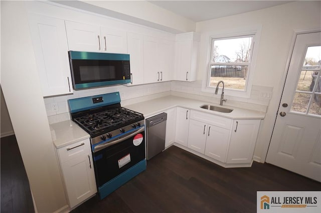 kitchen featuring light countertops, white cabinets, appliances with stainless steel finishes, and a sink