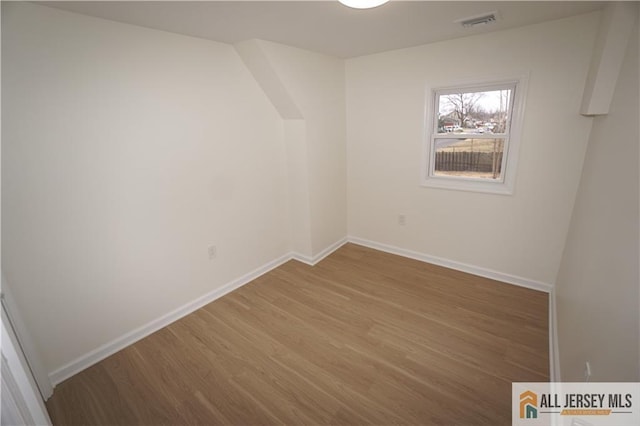 spare room with visible vents, baseboards, and wood finished floors