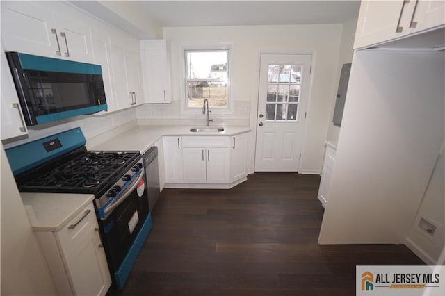 kitchen with dark wood-type flooring, a sink, white cabinets, light countertops, and stainless steel range with gas stovetop